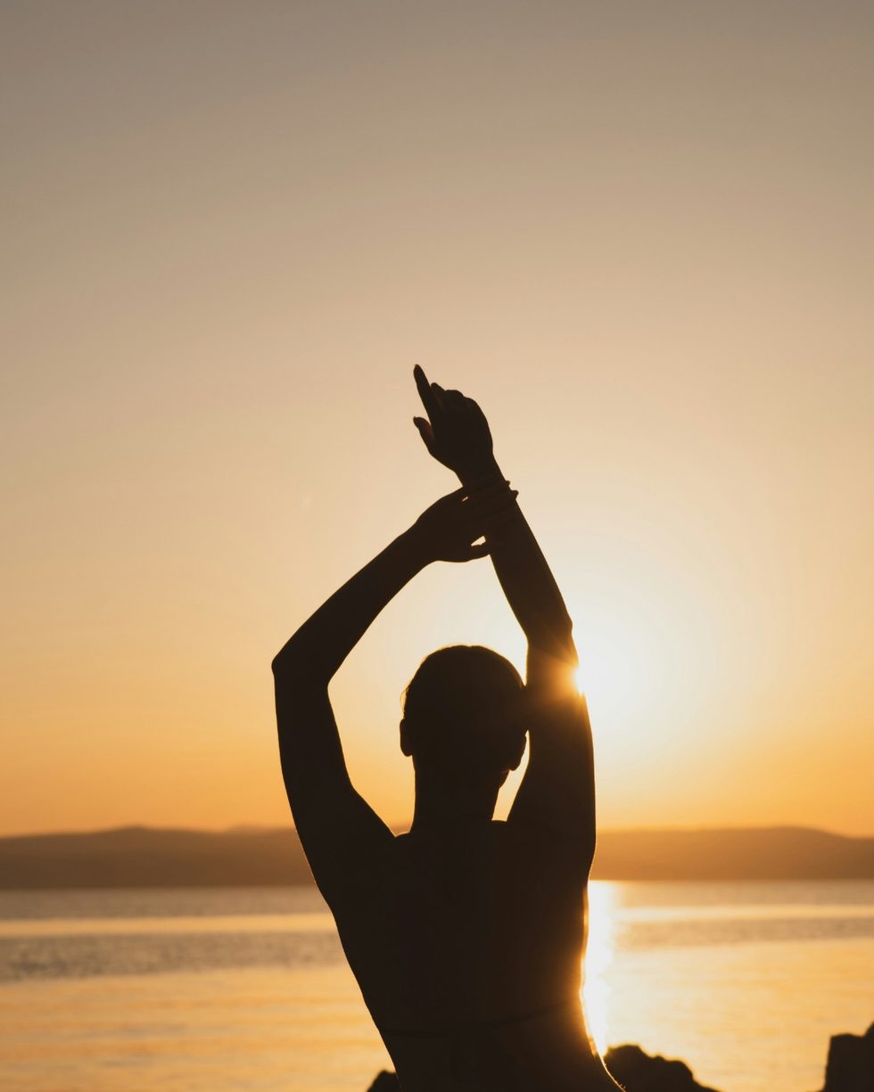 A woman stretching at sunset by the water